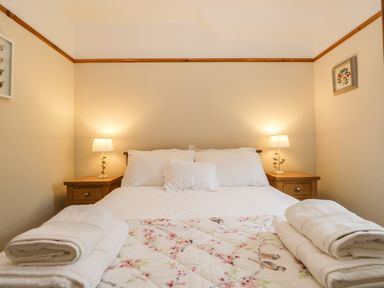 A bedroom with a double bed two bedside tables and lamps and folded towels on the bed at The Lodge in Greystoke