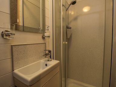 A bathroom with a sink and mirror next to a shower enclosure at Scafell Lodge Skiptory Howe 7 White Cross Bay Holiday Park near Windermere