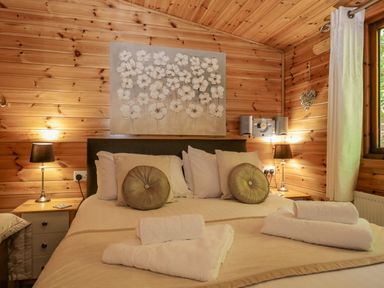 A bedroom with a double bed bedside tables lamps and folded towels at Scafell Lodge Skiptory Howe 7 White Cross Bay Holiday Park near Windermere