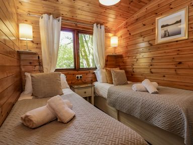 A bedroom with two single beds a nightstand and windows at Scafell Lodge Skiptory Howe 7 White Cross Bay Holiday Park near Windermere