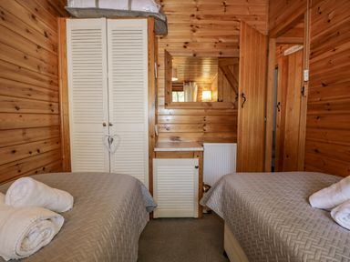 A wooden bedroom with two single beds and a wardrobe at Scafell Lodge Skiptory Howe 7 White Cross Bay Holiday Park near Windermere