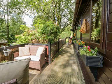 A wooden deck with outdoor seating and flower boxes on the wall at Scafell Lodge in Skiptory Howe 7 White Cross Bay Holiday Park near Windermere