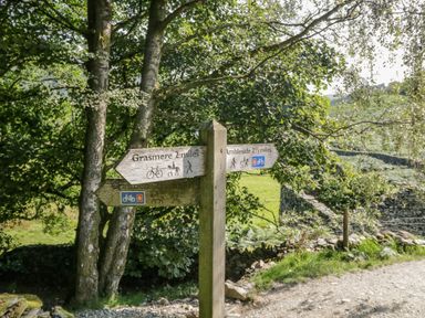 A wooden signpost with directions to Grasmere and Ambleside on a walking and cycling path at Scafell Lodge Skiptory Howe 7 White Cross Bay Holiday Park near Windermere