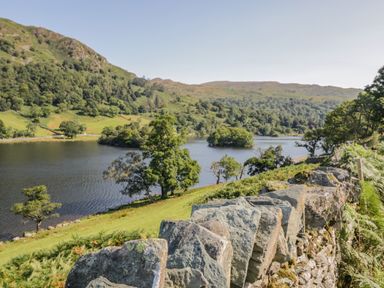 A stone wall beside a lake with trees and hills at Scafell Lodge Skiptory Howe 7 White Cross Bay Holiday Park near Windermere