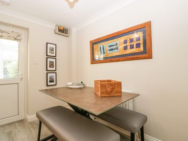 A dining area with a rectangular table and two bench seats below a framed artwork and three framed photos on the wall at The Beach House in West Bay
