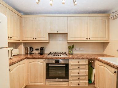 A kitchen with wooden cabinets a gas stove an oven countertop appliances and a sink at The Beach House in West Bay