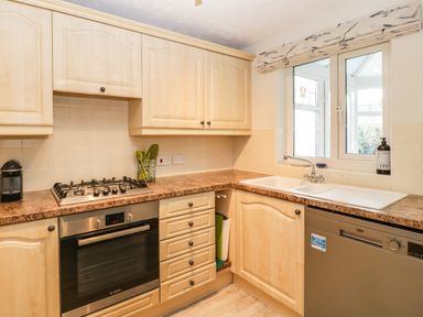 A kitchen with wooden cabinets a gas stove an oven a sink and a dishwasher at The Beach House in West Bay