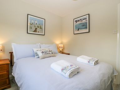 A bedroom with a double bed two bedside tables lamps and two framed pictures on walls at The Beach House in West Bay