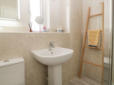A bathroom with a sink toilet ladder towel and window at The Beach House in West Bay