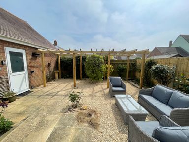 A backyard patio with outdoor seating and a wooden pergola at The Beach House in West Bay