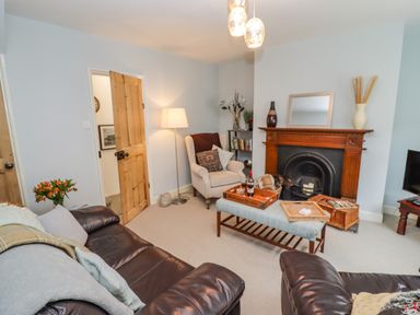 A living room with leather sofas a wooden fireplace and a coffee table at Anchor Cottage in Whitby