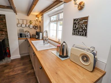 A kitchen countertop with a radio kettle microwave and hanging pans at Anchor Cottage in Whitby
