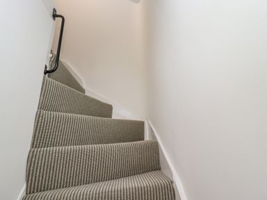 A narrow carpeted staircase with a handrail on the left at Anchor Cottage in Whitby
