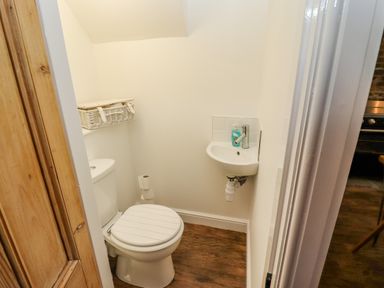 A small bathroom with a toilet sink and wicker basket at Anchor Cottage in Whitby