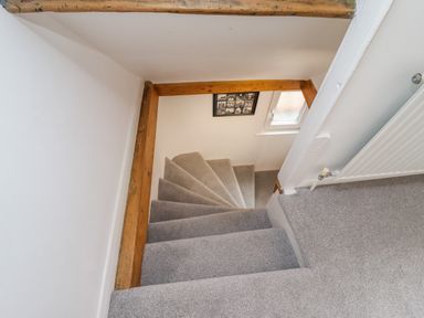 A carpeted staircase with wooden beams and a radiator on the wall at Anchor Cottage Whitby