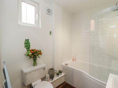 A bathroom with a bathtub shower toilet and flowers at Anchor Cottage in Whitby