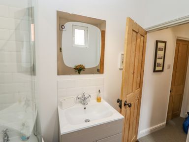 A bathroom sink with a mirror and wooden door at Anchor Cottage in Whitby