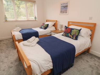 A bedroom with two single beds blue throws and animal print cushions at Brewers Cottage in Looe