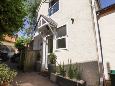 The exterior of a small house with a white door and windows and potted plants outside at Quayside Cottage in Teignmouth