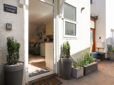 Entrance to a cottage with potted plants outside and a view into a kitchen and living area at Quayside Cottage in Teignmouth