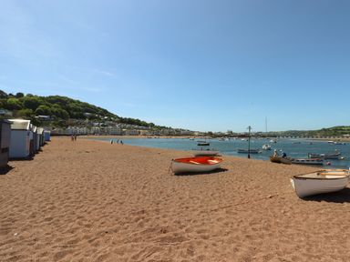 A beach with small boats on the sand and in the water with houses and trees in the background at Quayside Cottage in Teignmouth