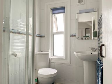 A bathroom with a toilet sink mirror window and shower at Quayside Cottage in Teignmouth