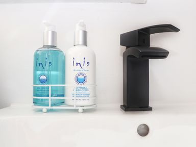 A bathroom sink with a black faucet and two bottles of Inis sea mineral hand wash and hand lotion at Pickney House Killigarth near Polperro