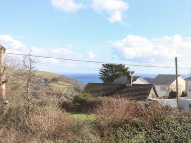 A view of houses and hills with the sea in the background at Pickney House in Killigarth near Polperro