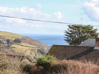 View of rolling hills sea and rooftops with power lines at Pickney House in Killigarth near Polperro