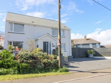 A white two-story house with a garden and driveway and a traffic sign in front at Pickney House in Killigarth near Polperro