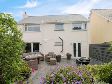 A backyard patio with outdoor furniture and flowers at Pickney House in Killigarth near Polperro