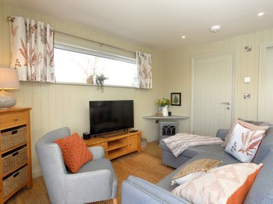 A living room with a gray sofa and armchair a wooden cabinet and a flat screen tv at The Swift in Wem