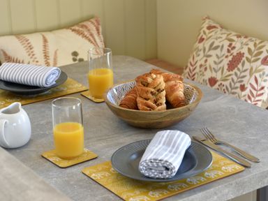 A dining table set with plates and rolled napkins croissants in a wooden bowl and glasses of orange juice at The Swift in Wem