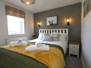 A bedroom with a bed with pillows and folded towels a nightstand and wall lights at The Swift in Wem