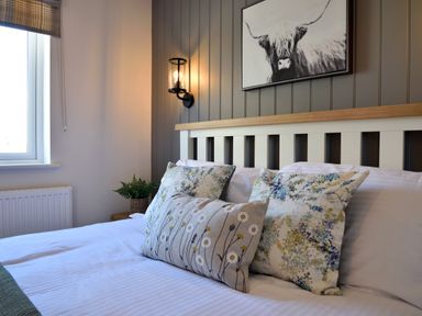 A bed with cushions and a framed picture on the wall above at The Swift in Wem