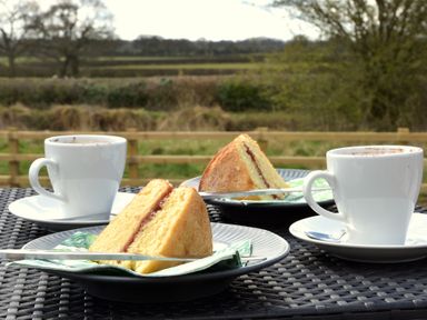 Two slices of cake on plates and two cups of coffee on an outdoor table at The Swift in Wem