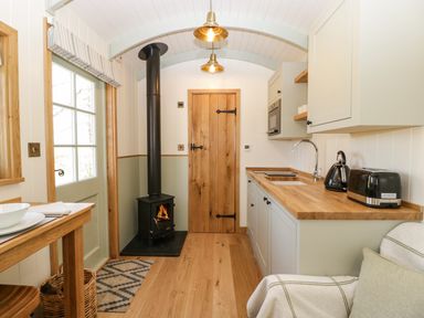 A small kitchen with wood burner stove kettle toaster and wooden countertop at Acorn in Bleadon