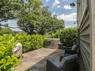 An outdoor area with a hot tub and seating at Acorn in Bleadon