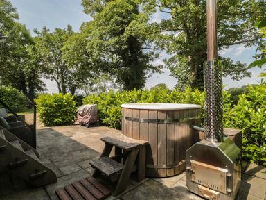 A hot tub and wooden bench with stove in the garden at Acorn in Bleadon