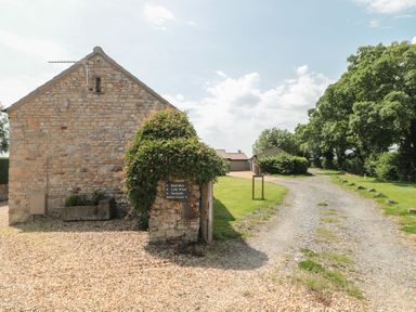 A stone building with a gravel path and parking area at Acorn in Bleadon