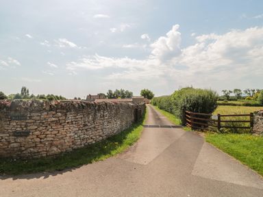 A dirt road with stone walls and a gate at Acorn in Bleadon