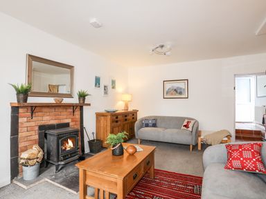 A living room with two grey sofas a wooden coffee table a fireplace and a wooden sideboard at 9 Ty Du Road in Llanberis