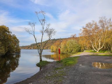 A lakeside path with trees and a red life buoy at 9 Ty Du Road in Llanberis