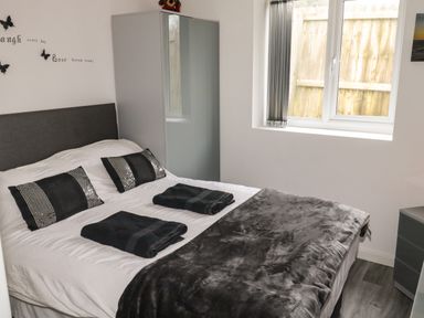 A bedroom with a bed dressed with black and white bedding two folded black towels on the bed a wardrobe near the window at Sunnydene in Paignton