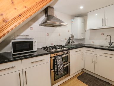 A kitchen with a microwave oven stove with oven hood white cabinets and a sink at Little Walton in Burnham-On-Sea