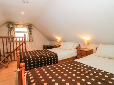 A bedroom with two single beds and wooden bedside tables with lamps at Little Walton in Burnham-On-Sea