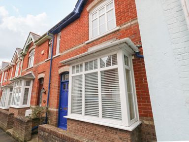 A row of brick houses with white windows and a blue door at ODYSEA in Weymouth