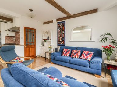 A living room with blue sofas and armchair a wooden door a white cabinet and a decorative wall hanging at ODYSEA in Weymouth