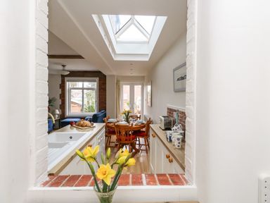 A kitchen and dining area with a skylight and a window view from the living room at ODYSEA in Weymouth
