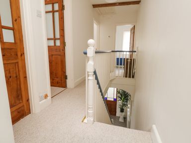 A hallway with carpeted floor wooden doors and a staircase with white railing at ODYSEA Weymouth
